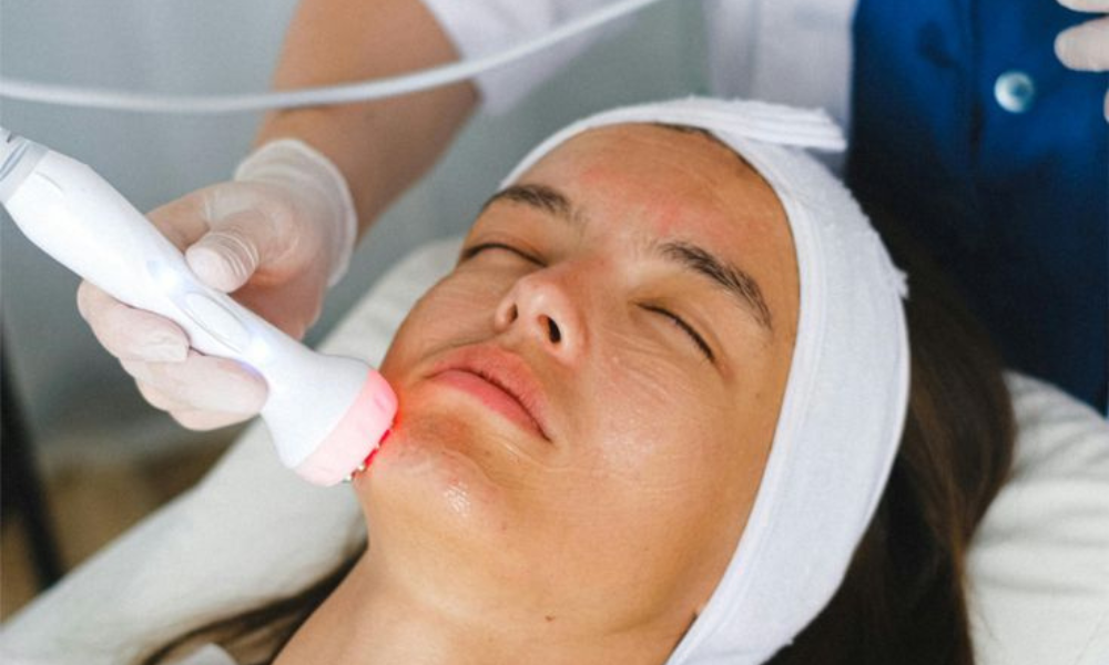 Facial treatment using a handheld skincare device on the chin.